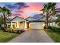 Charming single-story home with a brick driveway and well-maintained landscaping with palm trees at 14616 20Th E St, Parrish, FL 34219