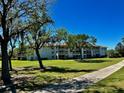 Scenic exterior view of the condo building surrounded by mature trees and an expansive lawn at 6505 Stone River Rd # 306, Bradenton, FL 34203