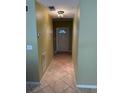 A tiled hallway that leads to the front door with warm wall paint and a ceiling light fixture at 5691 Bentgrass Dr # 15-102, Sarasota, FL 34235