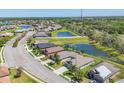 Aerial view of a residential neighborhood featuring homes, ponds, and green spaces under a clear sky at 11037 77Th E St, Parrish, FL 34219