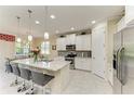 Bright kitchen with stainless steel appliances, a granite island with barstool seating, and white cabinetry at 116 Pescador Pl, Nokomis, FL 34275
