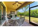 Relaxing screened-in patio features a ceiling fan and outdoor dining set with views of the well-maintained backyard at 116 Pescador Pl, Nokomis, FL 34275