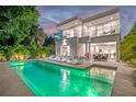 Backyard view of a modern home featuring a pool, lounge chairs, a dining area and balconies at 2327 Hillview St, Sarasota, FL 34239