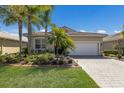 Beautiful single-story home with a well-manicured lawn, palm trees, red tile roof, and a paved driveway leading to an attached garage at 4134 63Rd E Ter, Sarasota, FL 34243