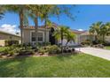 Charming single-story home featuring a red tile roof, lush landscaping, and a paved driveway leading to an attached garage at 4134 63Rd E Ter, Sarasota, FL 34243