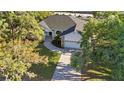An aerial view of a home with a well-maintained lawn, brick driveway, and mature trees surrounding the property at 4444 Robin Hood Trl W, Sarasota, FL 34232