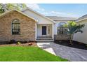Inviting front entrance with brick accents, a stone walkway, and a dark-colored front door at 4444 Robin Hood Trl W, Sarasota, FL 34232