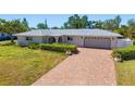 Beautiful one-story home with a manicured lawn, mature landscaping, hardscaped driveway, and two-car garage at 5522 Yorkshire Way, Sarasota, FL 34231
