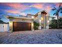 Attractive two-story home featuring a large garage, brick driveway, and manicured landscaping at 606 Crestwood Ln, Holmes Beach, FL 34217