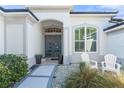 Attractive home entrance with a modern front door, decorative stone landscaping, and charming outdoor seating at 826 Oak Briar Ln, Osprey, FL 34229