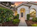 Inviting front entrance with decorative landscaping and charming arched windows at 9408 Glen Abbey Ln, Sarasota, FL 34238