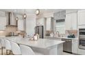 Modern kitchen with stainless steel appliances, a large island with seating, pendant lighting, and white cabinetry at 14919 Contenta Loop, Bradenton, FL 34211