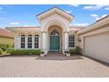 Inviting front exterior showcasing a beautifully arched entryway, pristine landscaping, and a paver driveway at 150 Medici Ter, North Venice, FL 34275