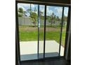 View of the backyard, as seen through sliding glass doors, overlooking green space and a white fence at 4656 Pleasant Ave, Palm Harbor, FL 34683