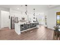 Modern kitchen with white cabinets, stainless steel appliances, an island with barstool seating and wood flooring at 4820 Coastal Days Ln, Bradenton, FL 34211