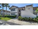 Condo exterior shows lush lawn, garden beds, covered main entry, and second story balcony at 5630 Golf Pointe Dr # 205, Sarasota, FL 34243