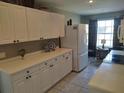Kitchen area showcasing white cabinets and modern appliances, including a refrigerator and cooktop stove at 6821 Fairview Ter # 6821, Bradenton, FL 34203