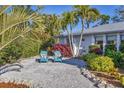 Inviting outdoor seating area with two blue Adirondack chairs surrounded by lush tropical landscaping at 7612 4Th Avenue Nw Dr, Bradenton, FL 34209