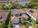 Beautiful home with solar panels, tile roof, paver driveway, lush landscaping, and a community lake view at 18013 Polo Trl, Bradenton, FL 34211
