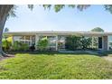 Home exterior view with wall of windows and beautiful manicured lawn at 3289 Fairhaven Ln # 112, Sarasota, FL 34239