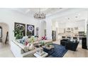 Spacious living room with high ceilings, modern chandelier, and an open floor plan leading to the kitchen at 4706 Balboa Park Loop, Bradenton, FL 34211
