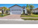 Inviting home featuring a two-car garage, brick driveway, and lush landscaping for enhanced curb appeal at 510 16Th E Ave, Palmetto, FL 34221