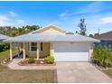 Charming one-story yellow home with an attached two-car garage and well-maintained landscaping at 5319 Levi Ln, Sarasota, FL 34233