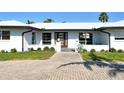 Charming single-story home featuring a modern white exterior, complemented by lush landscaping and a brick walkway to the front door at 537 Gunwale Ln, Longboat Key, FL 34228
