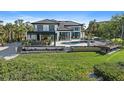 A modern home with a swimming pool, an outdoor kitchen, a patio with ample seating, and lush green landscaping at 6178 9Th Avenue Ne Cir, Bradenton, FL 34212