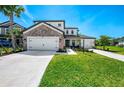 Charming two-story home with a stone facade, well-maintained lawn, and a spacious three-car garage at 9487 Tequila Sunrise Dr, Sarasota, FL 34241