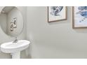 Stylish powder room featuring pedestal sink, oval mirror, and framed artwork at 11818 Davis Dr, Largo, FL 33774