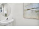 Modern powder room with a sleek pedestal sink, round mirror, and tasteful artwork at 11830 Davis Dr, Largo, FL 33774