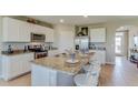 Bright kitchen featuring white cabinets, granite countertops, stainless steel appliances, and an island with seating at 12128 Kingsley Trl, Parrish, FL 34219