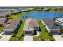 Aerial view of home with verdant lawn, landscaping, and a serene lake in the background at 14147 Campfire Ct, Parrish, FL 34219