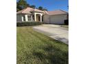 Inviting single-story home with a tile roof, lush lawn, and a paved driveway leading to the attached garage at 2097 Wasatch Dr, Sarasota, FL 34235