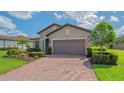 View of the home's garage with a brick driveway, and manicured lawn in a well-maintained community at 5562 Rain Lily Ct, Sarasota, FL 34238