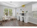 Bright office with two windows, hardwood floors, dual white desks with shelving and storage, and white chairs at 5954 Anise Dr, Sarasota, FL 34238