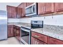 Close-up of kitchen with granite countertops, stainless steel appliances, and dark wood cabinets at 8657 Milestone Dr, Sarasota, FL 34238