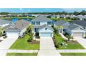 Overhead view of a charming two-story home with a well-manicured lawn and a serene lake backdrop at 10614 Morning Marsh Ln, Parrish, FL 34219