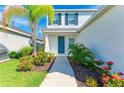 Inviting front entrance with a vibrant blue door and lush, colorful landscaping at 10614 Morning Marsh Ln, Parrish, FL 34219