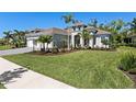 Landscaped home featuring tropical palm trees and a well-manicured lawn at 12352 Auburndale Ct, Venice, FL 34293