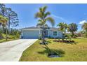 Inviting single-story home with a manicured lawn, mature trees, and a long driveway leading to the garage at 145 Baytree Dr, Rotonda West, FL 33947