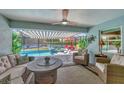 Cozy covered outdoor patio with comfortable seating, ceiling fan, and views of the screened-in pool area at 145 Baytree Dr, Rotonda West, FL 33947