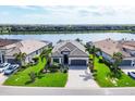 Aerial view of a home with a gray tile roof near a lake in a residential community at 17604 Hickok Belt Loop, Bradenton, FL 34211