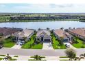 Aerial view of three homes with manicured lawns and a serene lake backdrop in a residential community at 17604 Hickok Belt Loop, Bradenton, FL 34211