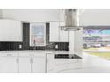 Modern kitchen featuring a sleek black backsplash, white cabinets, and stainless steel range hood at 203 22Nd Ne St, Bradenton, FL 34208