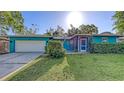 Charming single-story home with a two-car garage, lush lawn, and vibrant turquoise exterior at 2261 Linwood Dr, Sarasota, FL 34232