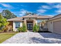 Inviting home with stone accents, a manicured lawn, and a brick-paved driveway leading to the garage at 2439 Sonoma W Dr, Nokomis, FL 34275