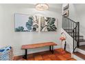 Elegant foyer featuring terracotta tile flooring, a wooden bench, tropical artwork, and a staircase at 4002 6Th Ave, Holmes Beach, FL 34217