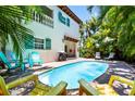 Inviting backyard with a private pool surrounded by lush greenery, sun loungers, and colorful chairs at 4002 6Th Ave, Holmes Beach, FL 34217